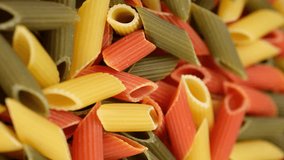 Raw three coloured Italian pasta penne, rotation. Vertical video