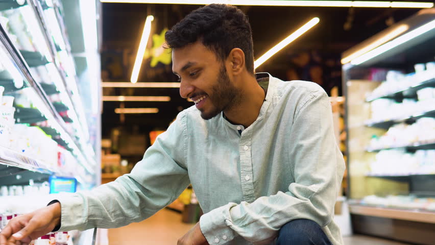 Indian man shopping dairy product in grocery store. Side view of handsome man buying ice cream | Shutterstock HD Video #1108736621