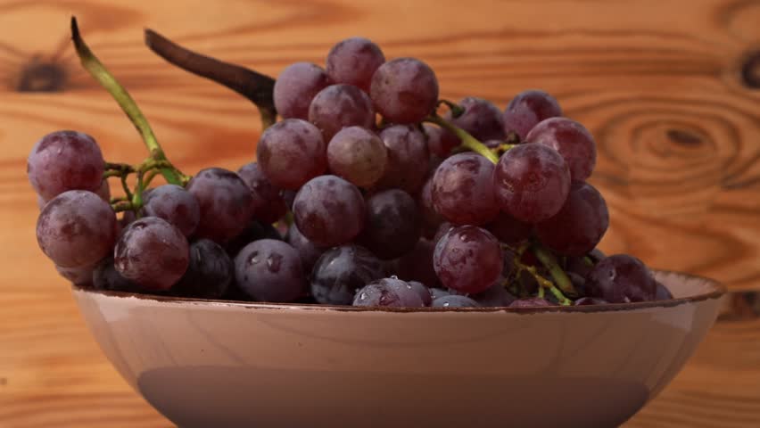 Red grapes rotate on a wooden background. Ripe red grapes.
