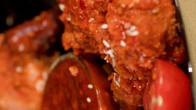 Vertical video. Female fingers take a chicken wing from a bowl with ketchup on the table.
