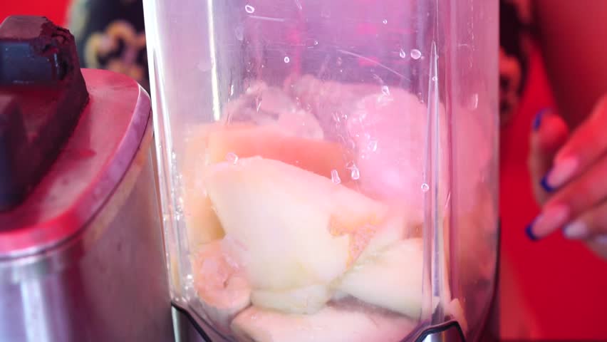 Woman making a fruit cocktail in a blender, smoothies preparation with melon and banana. woman puts cubs of ice and pieces of melon into a blender. Healthy summer drink concept. | Shutterstock HD Video #1108737309