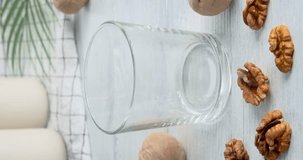 Pouring walnut milk in glass. Closeup video with vegan drink made of walnuts poured in glass on white wooden table, 4k vertical video clip, slow motion footage, non-dairy product
