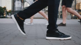 Side view following male feet crossing busy street. Man wearing casual dark trousers leather sneakers goes on pedestrian crossing in big city. Low angle people crowd legs walking urban sidewalk - Powered by Shutterstock - Get 15% off with code: PIKWIZARD15