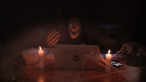 Skeleton character of death in fog beckons with bony hand show rocker symbol, in dark room near laptop and candles in cobwebs. Horror-loving friends to scariest Halloween party ever.  - Powered by Shutterstock - Get 15% off with code: PIKWIZARD15