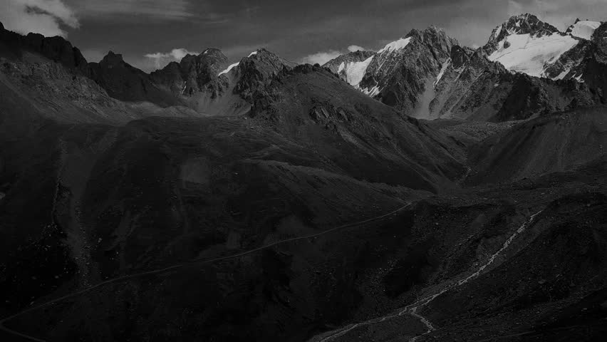 Stylised in an old archived style footage view of mountains with glaciers. 4K black and white video with noise and scratches effects.