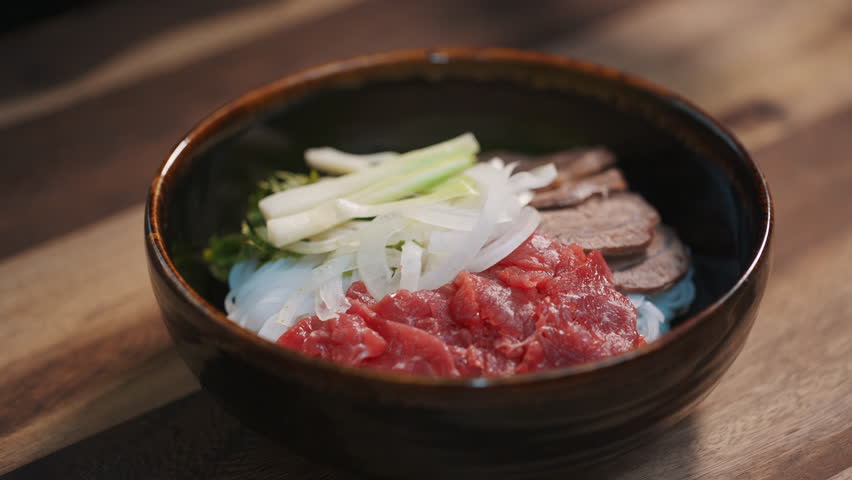 Chef places Red Chili Pepper on Vietnamese Beef Noodle Soup