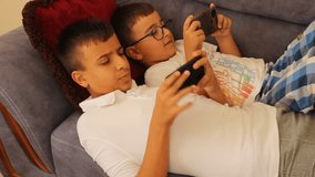 little turkish brothers playing mobile games together on the phone while lying down	