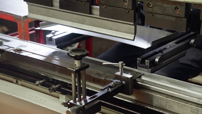 Bending machine operator bends sheet metal product. Employee works at metal factory. Bending sheet metal on hydraulic machine. Close-up in 4K, UHD Royalty-Free Stock Footage #1108752021