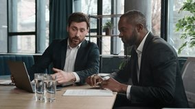 Diverse multiracial African American and Caucasian men colleagues coworkers businessmen financial agents discuss business project startup with laptop in office work with papers documents paperwork - Powered by Shutterstock - Get 15% off with code: PIKWIZARD15