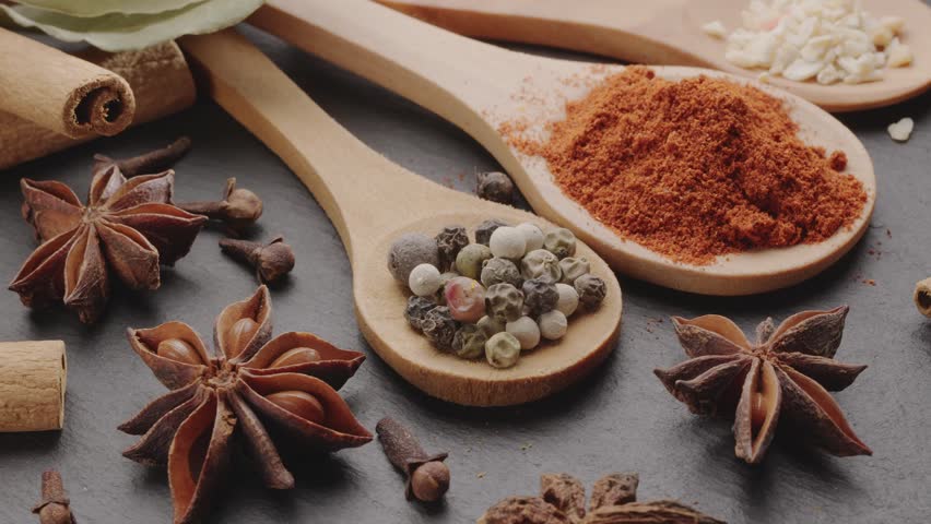 Various types of spices on wooden spoons slowly move along the frame, a great food background for your projects.