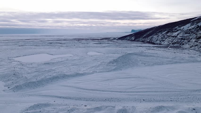 Aerial panoramic view over Skaftafellsjokull glacier surrounding mountains, in Iceland, covered in snow, at sunset