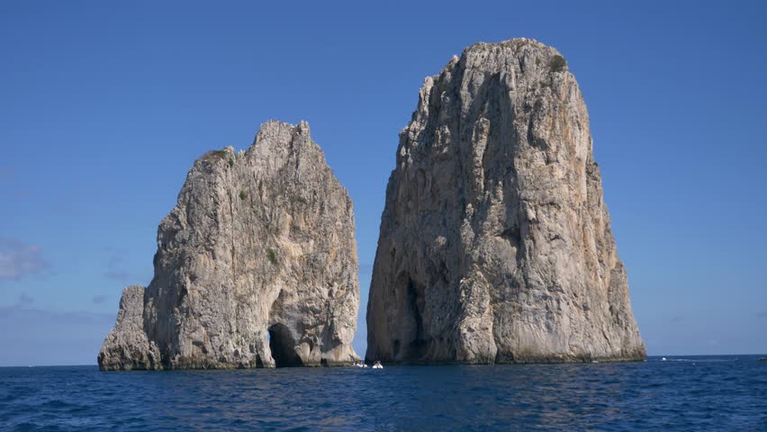 Faraglioni of Capri, the Faraglione di mezzo and Faraglione di fuori, also called Scopolo, Rock Stacks in the Tyrrenean Sea in Southern Italy Royalty-Free Stock Footage #1108759627