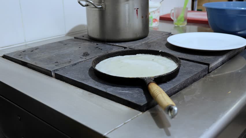 Large round pancake in a frying pan. Cooking smoke goes up from the pancake. Shrovetide holiday, a vital holiday of the meeting of spring among the Slavs. | Shutterstock HD Video #1108760005