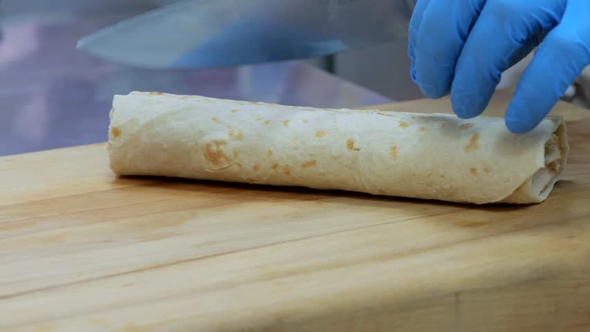 Shawarma in pita bread, shawarma pita vegetables fried potatoes cabbage onions, close-up of the process of cooking shawarma in pita bread, cooking tongs put vegetables on pita bread. | Shutterstock HD Video #1108760031