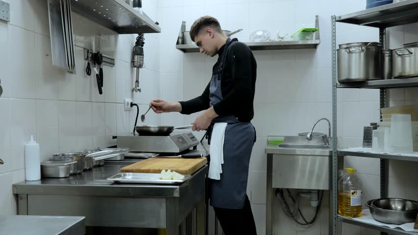 A professional chef prepares a gastronomic dish in a frying pan using ingredients and kitchen utensils. The chef is cooking in the kitchen of the restaurant. Cook's work in the kitchen. | Shutterstock HD Video #1108760053