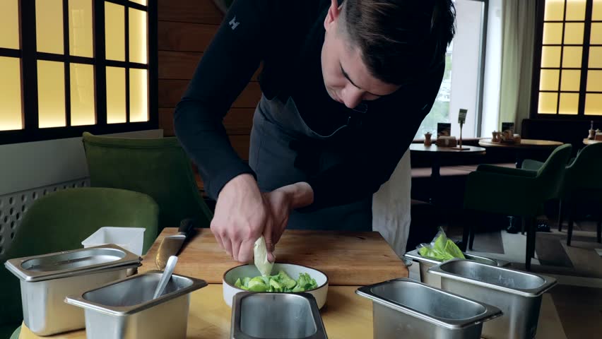 Healthy organic food. The cook prepares a salad with cucumber and radish, the cook prepares a light salad, vegetarian food, a handsome caucasian male cook presents a delicious dish | Shutterstock HD Video #1108760059