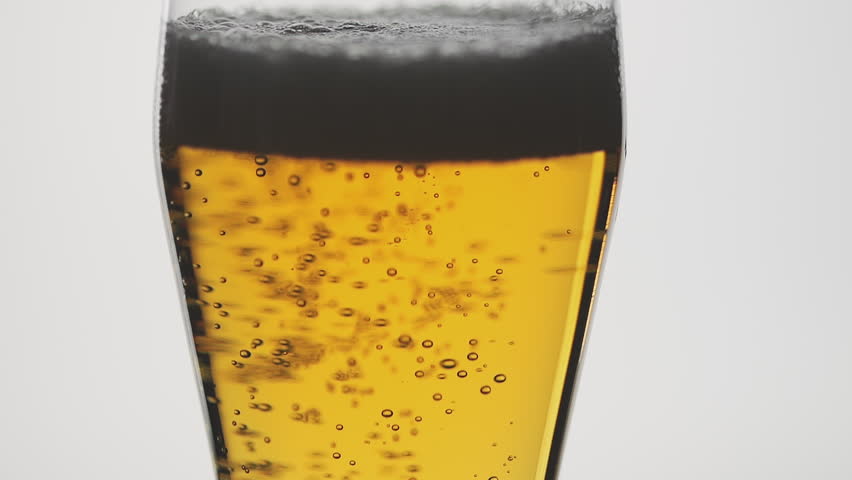 Bubbles rise in a glass of foamy beer on a white background