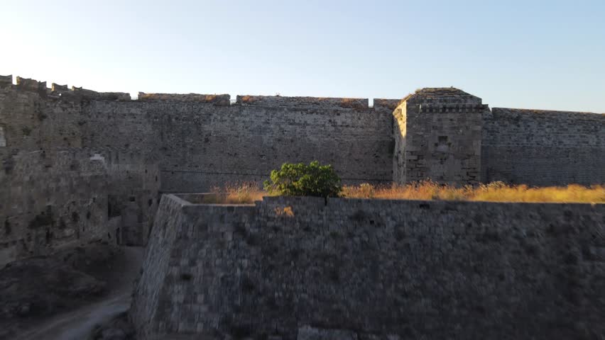 Aerial forward over fortification walls of old town Rhodes to historic palace