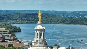 Aerial shot of gilded bronze statue, "Wisconsin" on top of capitol building dome in Madison, WI. Long telephoto zoom orbit with Lake Mendota in background on summer day. - Powered by Shutterstock - Get 15% off with code: PIKWIZARD15