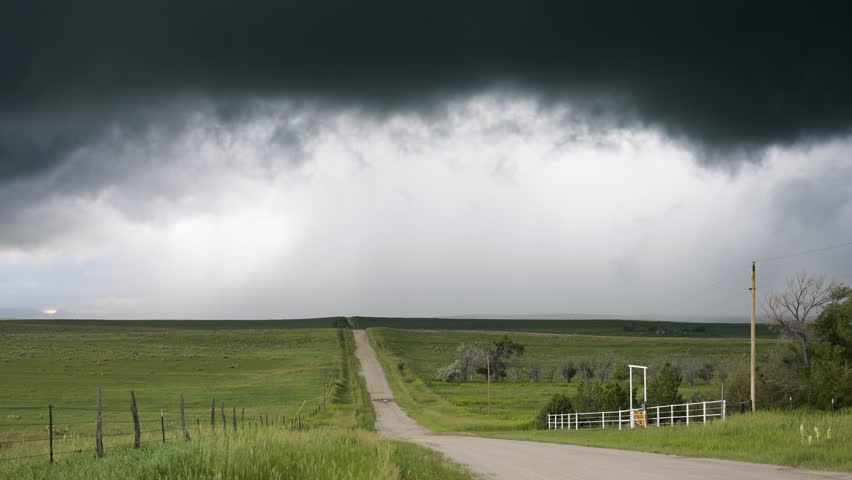 Country Road And Rolling Hills As Dark Textured Clouds Move Over Head .