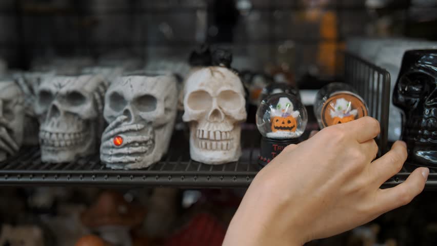  Halloween. shopping for Halloween party. close-up. ceramic figurines of skulls. small glass balls with sparkles and pumpkins. Halloween accessories are on shelves in a store. Halloween decorations. p Royalty-Free Stock Footage #1108768581