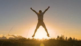 LENS FLARE: Young guy jumps with raised arms on a grassy mountaintop at sunset. He is celebrating as he reaches the top when first rays of autumn morning sun start spilling over the alpine hilltop. - Powered by Shutterstock - Get 15% off with code: PIKWIZARD15