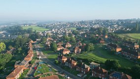A drone's view of Dewsbury Moore Council estate, UK, displays red-brick housing and the industrial Yorkshire landscape on a sunny morning.