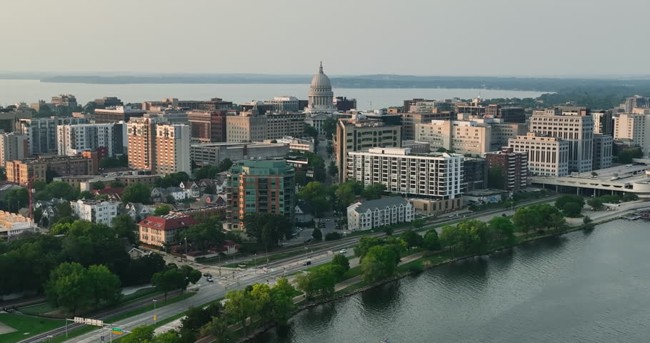 Flying backwards above Lake Monona in Madison, Wisconsin. City skyline with Wisconsin Capitol building