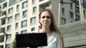 A cute teenage girl with long hair in a fashionable outfit maintains her personal blog, shoots a video on a smartphone outdoors