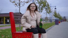 Young upset pregnant woman with beer bottle and cigarette searching lighter in pocket. Portrait of careless depressed Caucasian expectant smoking drinking outdoors on windy cloudy autumn day - Powered by Shutterstock - Get 15% off with code: PIKWIZARD15