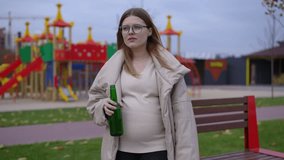 Portrait of sad pregnant woman with beer bottle standing on childrens playground looking around thinking. Caucasian depressed frustrated expectant with alcohol outdoors - Powered by Shutterstock - Get 15% off with code: PIKWIZARD15