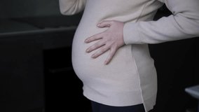 Side angle view unrecognizable pregnant woman caressing belly drinking beer from bottle standing indoors. Young Caucasian expectant with alcohol at home in kitchen - Powered by Shutterstock - Get 15% off with code: PIKWIZARD15