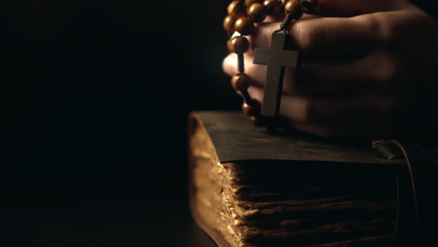 Hands folded in prayer on a Holy Bible in church. Woman praying with a wooden cross. Spirituality religion and hope concept. Supplication believe and faith. Abstract vintage religious dark background Royalty-Free Stock Footage #1108780199