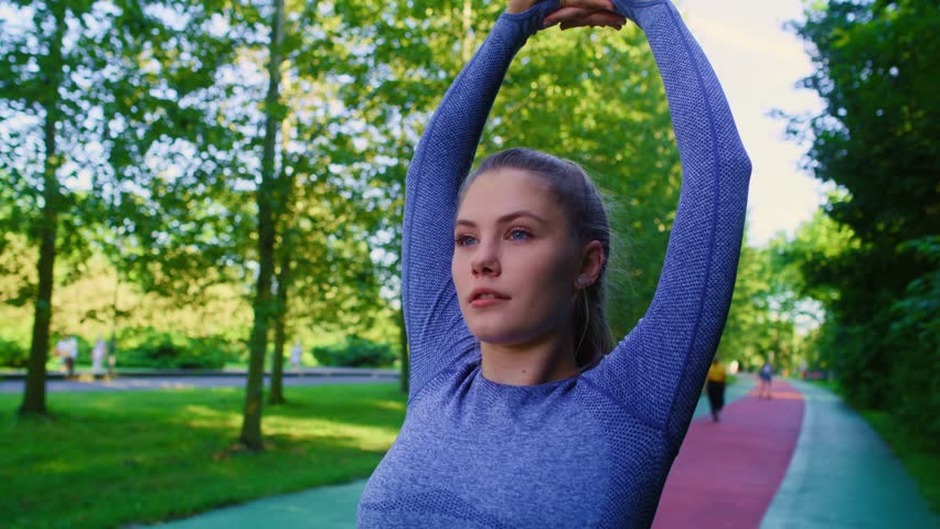 Young caucasian woman stretching before jogging in the park. Shot with RED helium camera in 8K.  