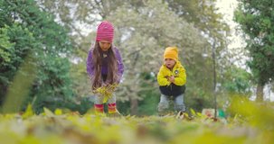 Autumn season outside and kids boy and girl playing with autumn fallen leaves