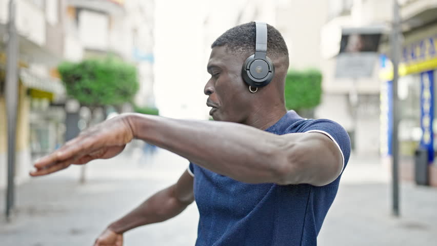 African american man listening to music and dancing at street