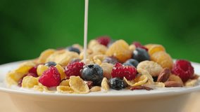 Pour milk on crunchy granola cereals. Morning eating with flakes, raspberries, blueberries, nuts, oatmeal. Healthy breakfast concept, Healthy food, clean eating, closeup, rotation background - Powered by Shutterstock - Get 15% off with code: PIKWIZARD15