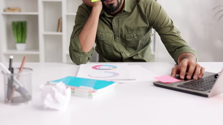 The concept of a lot of work. Tired Indian student boy sleeping with stickers on his eyes while sitting at the table. Distracted man in home office.