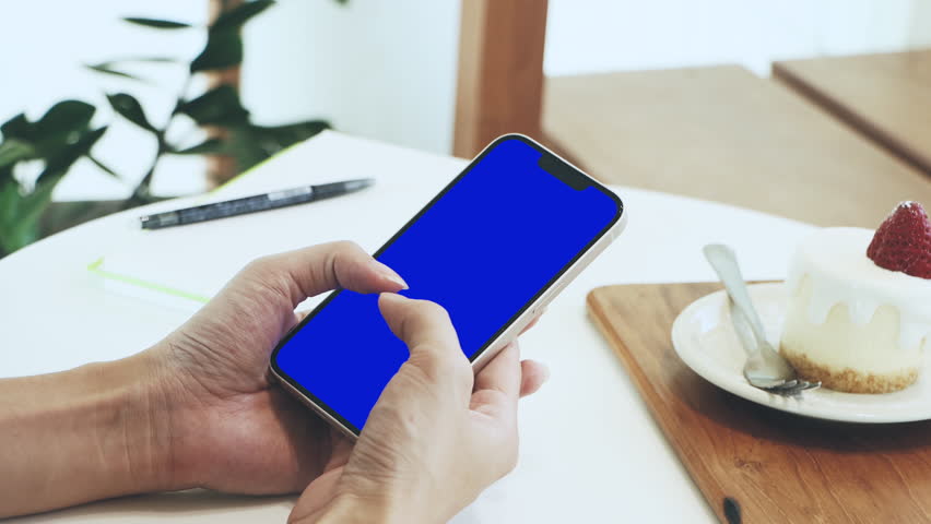 Blank screen smartphone blue display background. Woman using and holding mobile phone working from home 4K video. Technology.