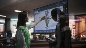 Black Female Game Designer Talking to Asian Female Project Manager And Standing Next To TV Set With 3D Game Character On Screen. Diverse Colleagues Discussing New RPG Game in Office. Slow Motion. - Powered by Shutterstock - Get 15% off with code: PIKWIZARD15