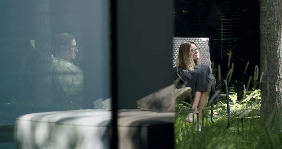 Young couple resting outdoors. Man and woman sitting in armchairs on backyard of cottage house, relax on nature at summer sunny day. Weekend concept