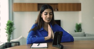 Young Indian woman talks to recruiter during on-line job interview virtual meeting using videocall application and smart phone sit at desk at home. Communication, modern technology usage, e-hiring