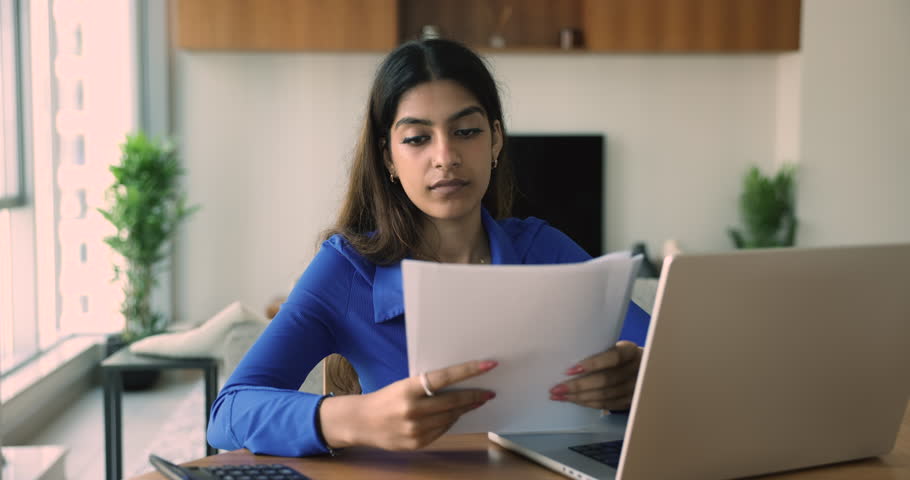 Young Indian woman sits at desk hold documents, read great news in paper notice from bank feel happy bank loan approval, receive good message, looks excited, university admission, invitation, grant Royalty-Free Stock Footage #1108798217