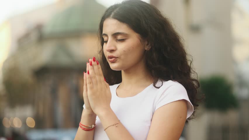 Portrait of hopeful young curly woman clasping hands in prayer asking for blessing and help at city centre outdoors Religion and faith concept Royalty-Free Stock Footage #1108801485