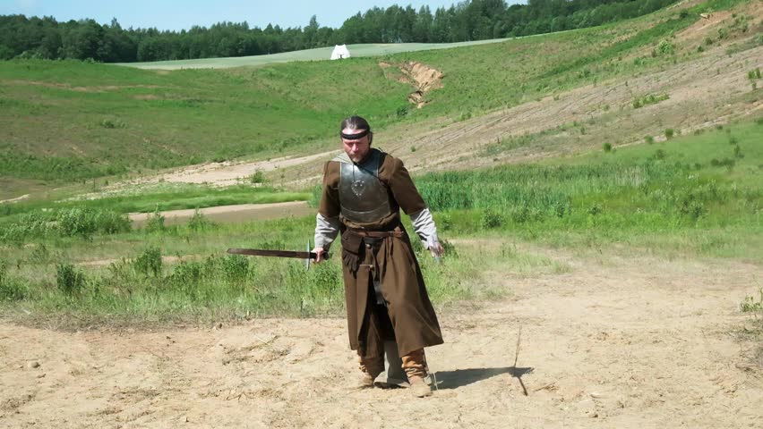 a guy dressed in a knight costume waves a sword, a man dressed in an ancient warrior costume waves a sword