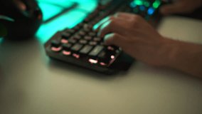 Young gamer plays a video game or typing on colorful keyboard, close up. Clip. Player uses gaming illuminated keyboard, concept of cybersport.