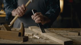 Crafting table. A woodworker works with a chisel, knocks chips out of wood, works with a tool in a woodworking shop, a wood specialist processes the material independently, at the workplace - Powered by Shutterstock - Get 15% off with code: PIKWIZARD15