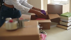 Tracking shot of happy African-American woman putting clothes into cardboard box to moving to new house. Happy black female packing belongings into cartoon box, getting ready for relocation apartment. - Powered by Shutterstock - Get 15% off with code: PIKWIZARD15