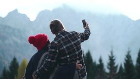 Young man and woman making selfie using smartphone on the mountain forest nature background. Couple in love dating outdoor. Two people hug and care each other. Romantic travel holiday vacation - Powered by Shutterstock - Get 15% off with code: PIKWIZARD15