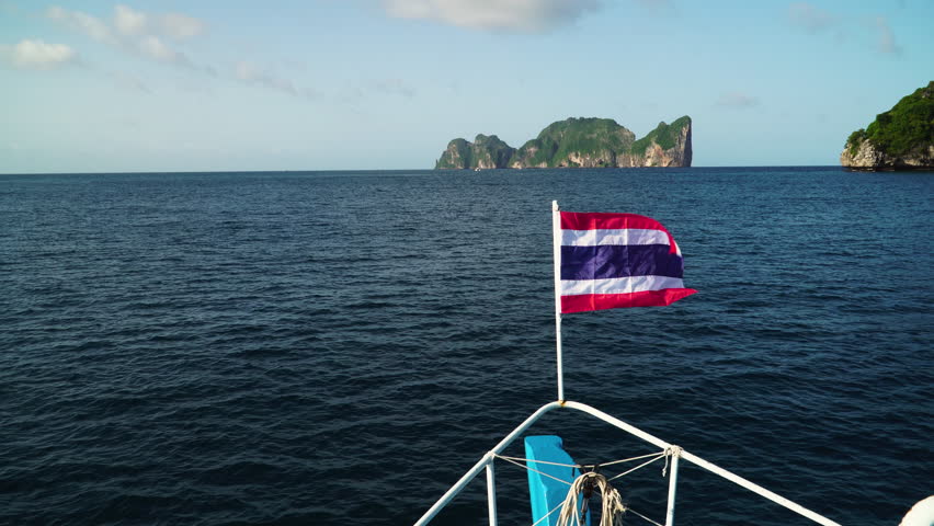 The flag of Thailand flies on the bow of a diving vessel near Pih Leh lagoon off Koh Phi Phi Island, Thailand. Handheld shot